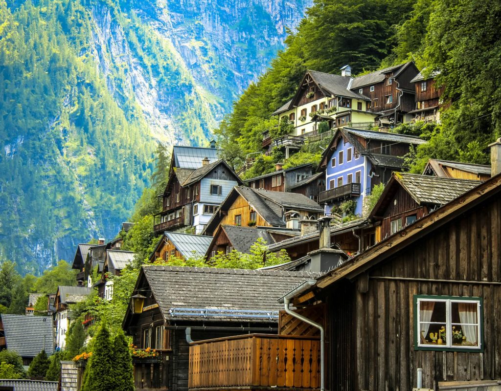 Charming wooden houses on a lush mountainside in Hallstatt, Austria under bright daylight.