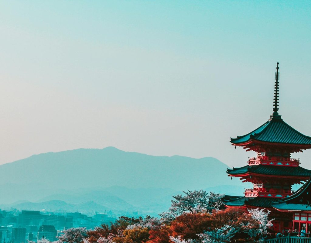 Scenic view of Kiyomizu-dera Temple with cherry blossoms in Kyoto, Japan, capturing traditional Japanese architecture at twilight.