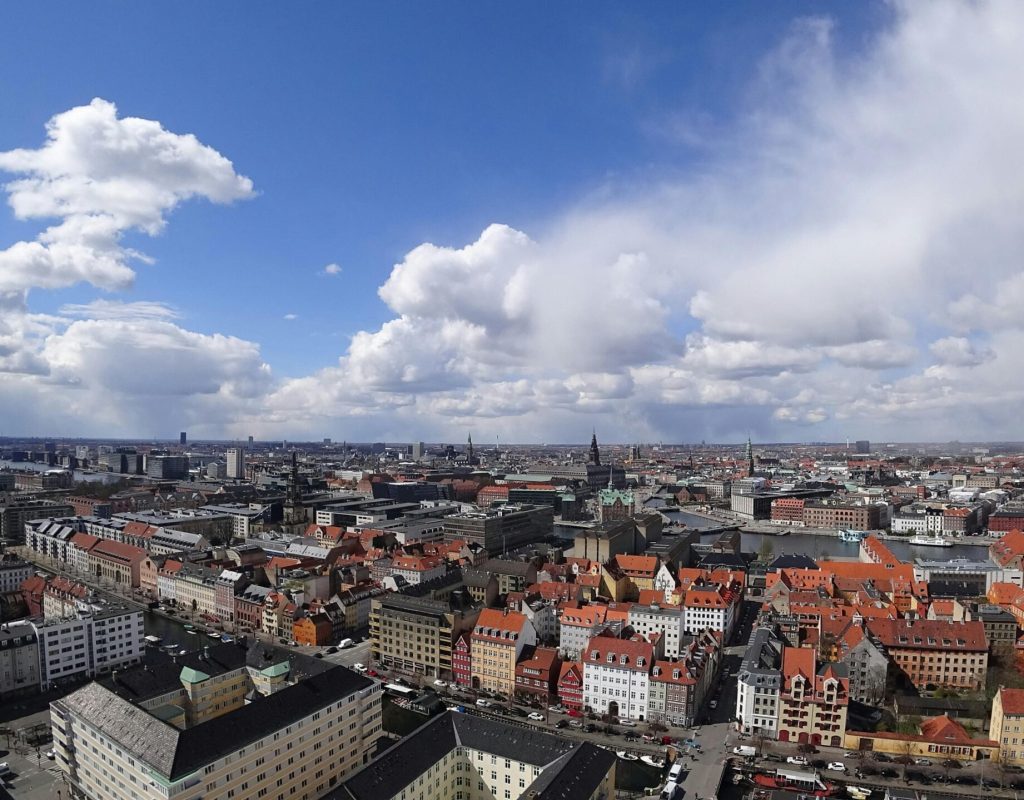 Panoramic aerial shot of Copenhagen, Denmark under a dramatic sky. Vibrant urban landscape.
