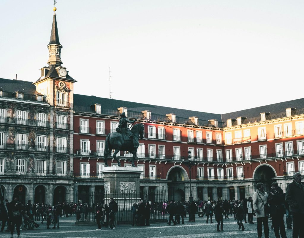 A lively scene at Plaza Mayor, Madrid, featuring historic architecture and a statue.